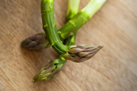 Close up of green asparagus on a wooden table in a kitchenの写真素材