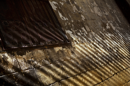 Rusty grilling on the window of an old stone wallの写真素材