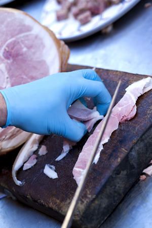 Chef cutting pieces of ham in a butcher shopの写真素材