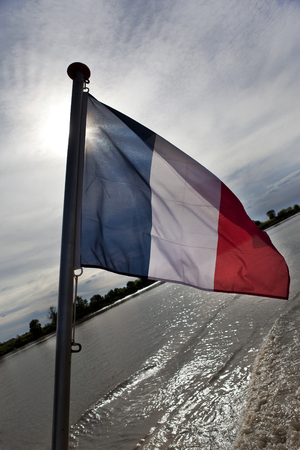 Sunset on a river and flag on a shipの写真素材