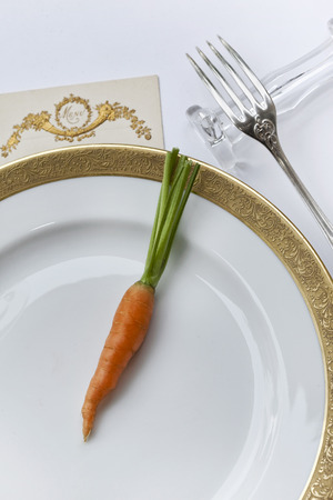 Carrot on a plate and menu on a luxury table setの写真素材