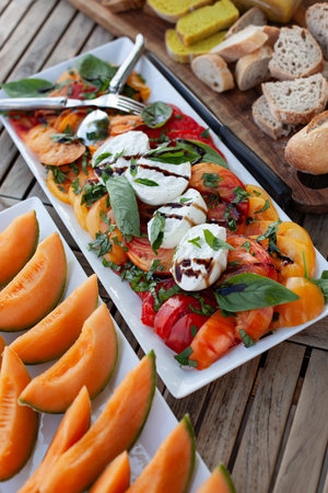 Tomato salad and melon on a tableの写真素材