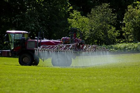 Tractor spraying crops in fieldの写真素材