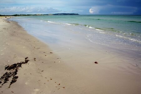 Empty sandy beach, sea waves, blue cloudy sky in Ebeltoft, Denmarkの写真素材