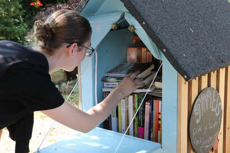 teenage girl picking book from free library on street in Bennebroek, the Netherlands, August 2021のeditorial素材