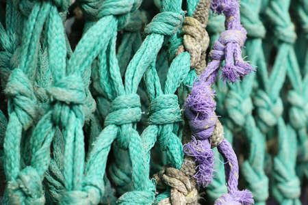 detail of old knotted fishing net or aqua colored nylon ropeの写真素材