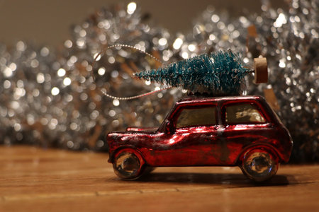 christmas decoration of red car with christmas tree on top with blurred silver garland in background