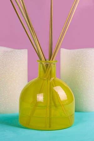 Glass Yellow Vase Diffuser and White Candles on Pink and Blue Backgroundの写真素材