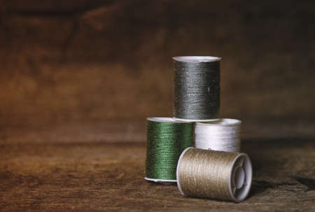 Set of Four Green and Khaki Sewing Spools on Wood Backgroundの写真素材