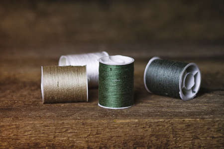 Set of Four Green and Khaki Sewing Spools on Wood Backgroundの写真素材