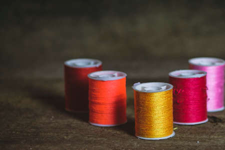 Set of Five Orange, Red and Pink Sewing Spools on Wood Backgroundの写真素材