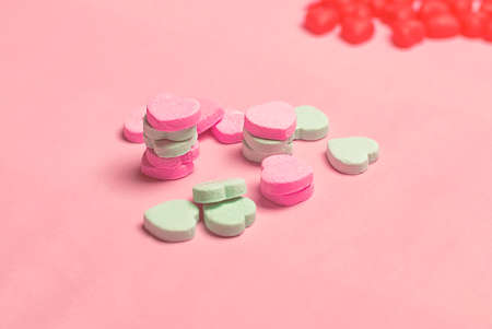 Pink and Green Candy Hearts on Pastel Pink Backgroundの写真素材