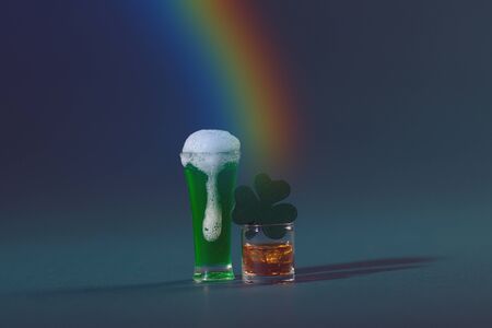 St. Patrick's Pint of Beer and Irish Whiskey with Wood Four Leaf Clover on a Green Background and Rainbowの写真素材