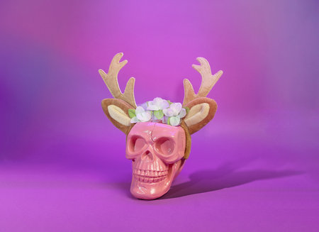 Skeleton of the Season: A Festive Skull with Antlers and Petals on a Purple Christmas Holiday Backgroundの写真素材