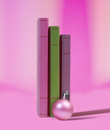 Pink Toned Holiday Composition with Christmas Ornament and Vertical Books  Cozy Reading Concept Photoの写真素材