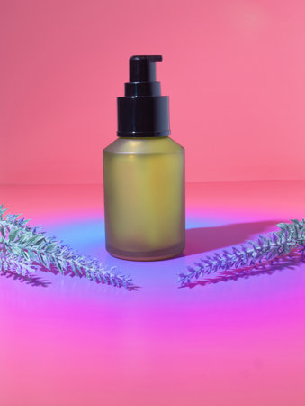 A Mock Up of a Yellow Green Beauty Cosmetic Bottle Packaging with Purple Lavender Sprigs on an Orange, Pink and Purple Dreamy Gradient Backgroundの写真素材