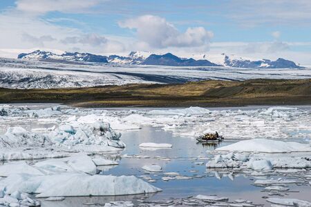 A tourist boat crossing the Jokulsarlon glacial lake in Icelandの写真素材