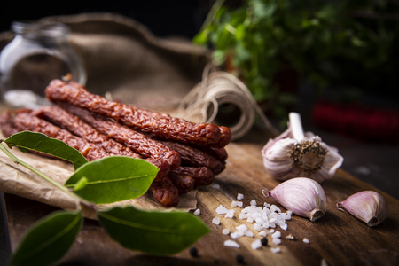 Smoked sausage, a composition of traditional dry, thin rural meats on a dark background. Regional food.の写真素材