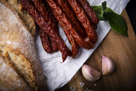 Smoked sausage, a composition of traditional dry, thin rural meats on a dark background. Regional food.の写真素材