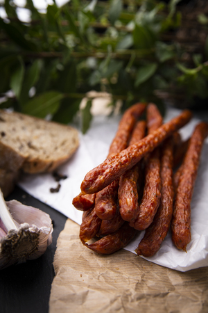 Smoked sausage, a composition of traditional dry, thin rural meats on a dark background. Regional food.の写真素材