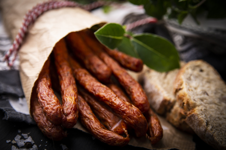Smoked sausage, a composition of traditional dry, thin rural meats on a dark background. Regional food.の写真素材
