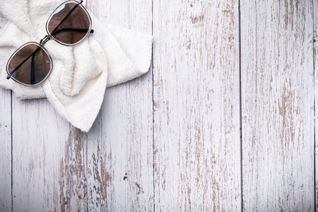 Composition of beach accessories, white towel and sunglasses on a wooden light background. Composition with space for text, top view.の写真素材