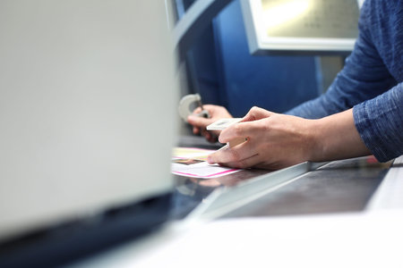 The printer at the stage watches the print quality through a magnifying glass.