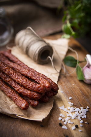 Smoked sausage, a composition of traditional dry, thin rural meats on a dark background. Regional food.の写真素材