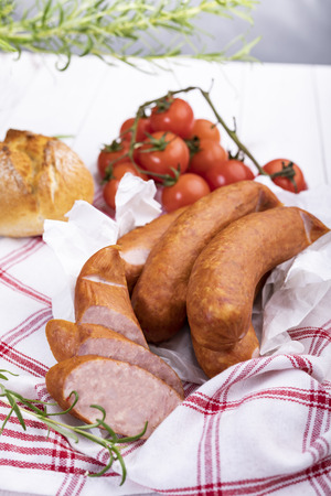 A thin traditional pork sausage in composition with fresh herbsの写真素材