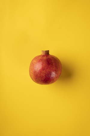 One pomegranate fruit isolated on a yellow backgroundの写真素材