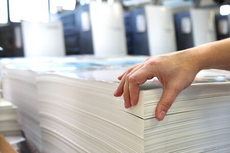 Work in the printing house, the employee checks the paper's weight.の写真素材