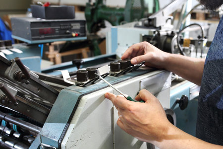 The employee repairs the printing press.