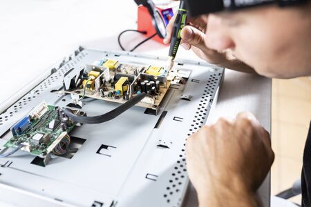 Computer repair in a professional service. A man with a screwdriver screwed screwsの写真素材