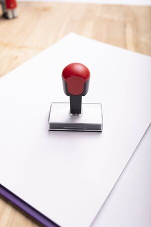A traditional ink rubber stamp placed on a paper folder. Office accessories on a wooden desk.の写真素材