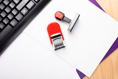 Two rubber stamps placed on a paper folder, next to the keyboard. A composition of office...