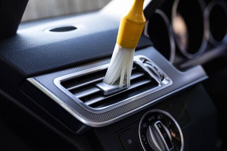 The man vacuums the interior details of the car with a brushの写真素材