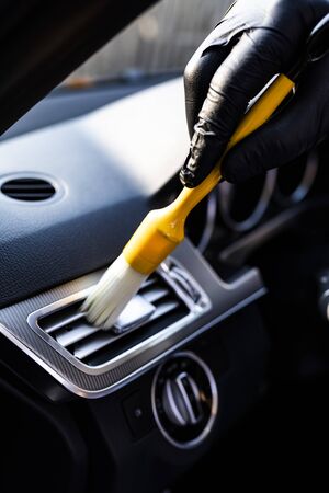 The man vacuums the interior details of the car with a brushの写真素材