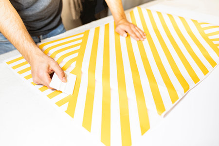 Man's hands covered with adhesive foil in yellow stripes.