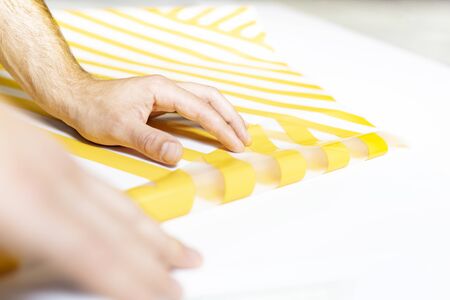 Man's hands covered with adhesive foil in yellow stripes.の写真素材
