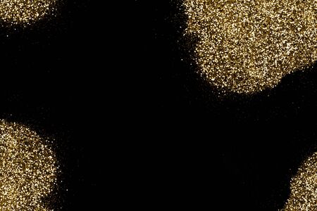 Golden glitter scattered on a deep black surface. Gold shining spots on black. Luxury background for Christmas, new year, birthday, special occasions, promotions, with a copy space.の写真素材