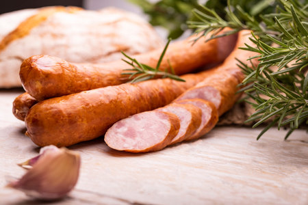 Smoked pork sausage on wood boards. Rustic composition of traditional sausage - in rings and cut...
