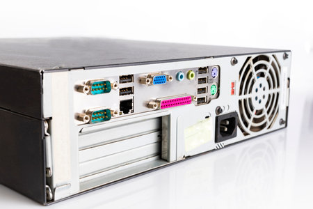 An old type, black computer desktop, CPU tower, back view with a fan, and USB and other ports. Computer hardware isolated on a white background.の写真素材