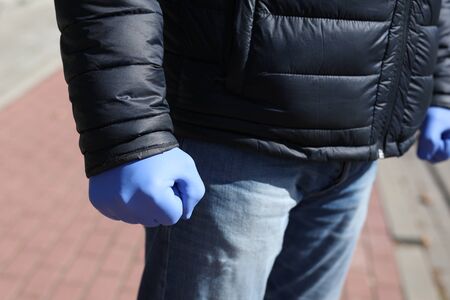 Protection against infections. Man in single use, protective, nitrile gloves standing outdoor on a sunny day.の写真素材