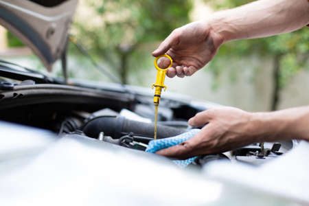 Checking car engine oil level with dipstick, under the hood of a car. Vehicle check-up.の写真素材