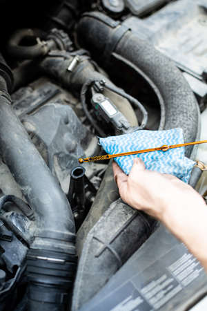 Checking car engine oil level with dipstick, under the hood of a car. Vehicle check-up.の写真素材