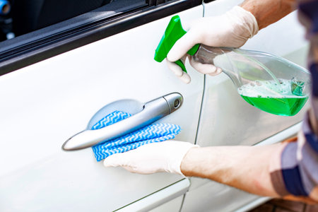 Auto detailing. Man in protective gloves, cleaning a car. Cleaning car exterior.