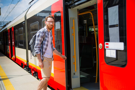 Tourist, traveller with a backpack, getting on a train on a platform on a suburban railway station.
