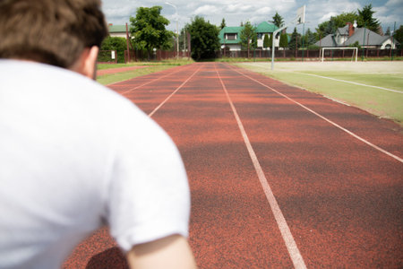 A starting position of a sprinter, focus on a running track.