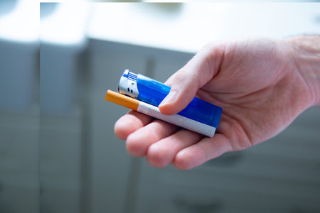 Nicotine addiction. Male hand holding a blue plastic lighter and a cigarette. Smoking break. Smoking habit.の写真素材