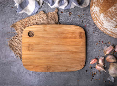 Wooden cutting board, spices, garlic, bread on dark stone countertop, background. Culinary concept, top view.の写真素材